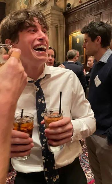 Fluffy laughing at a party with a drink in each hand